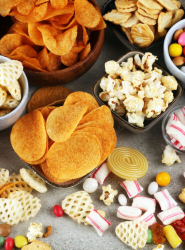 Salty snacks. Pretzels, chips, crackers and candy sweets on table